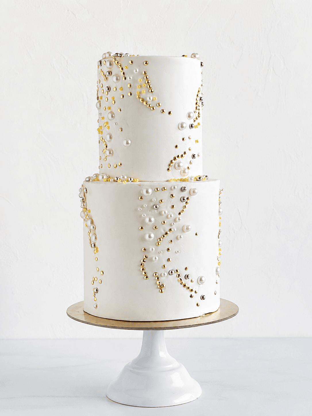 Torta scenografica bianca con perle oro e argento