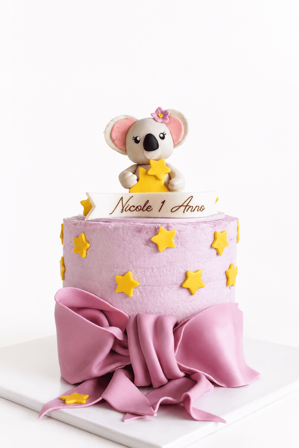 Torta rosa con grande fiocco, stelle gialle e koala