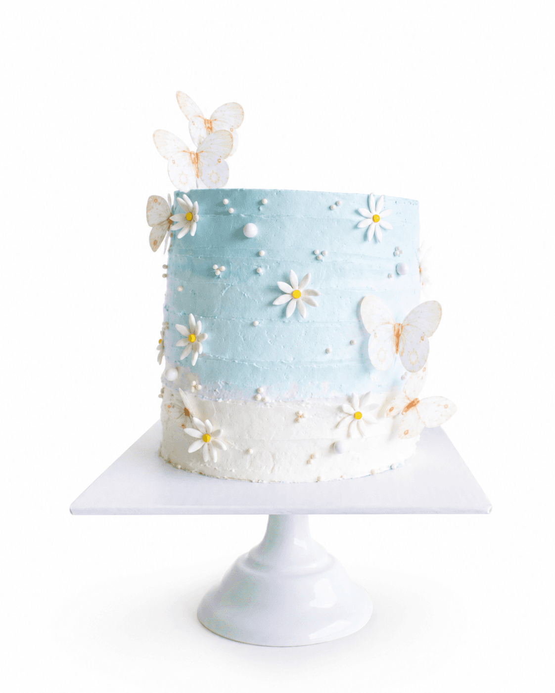 Torta azzurra e bianca con margherite e farfalle
